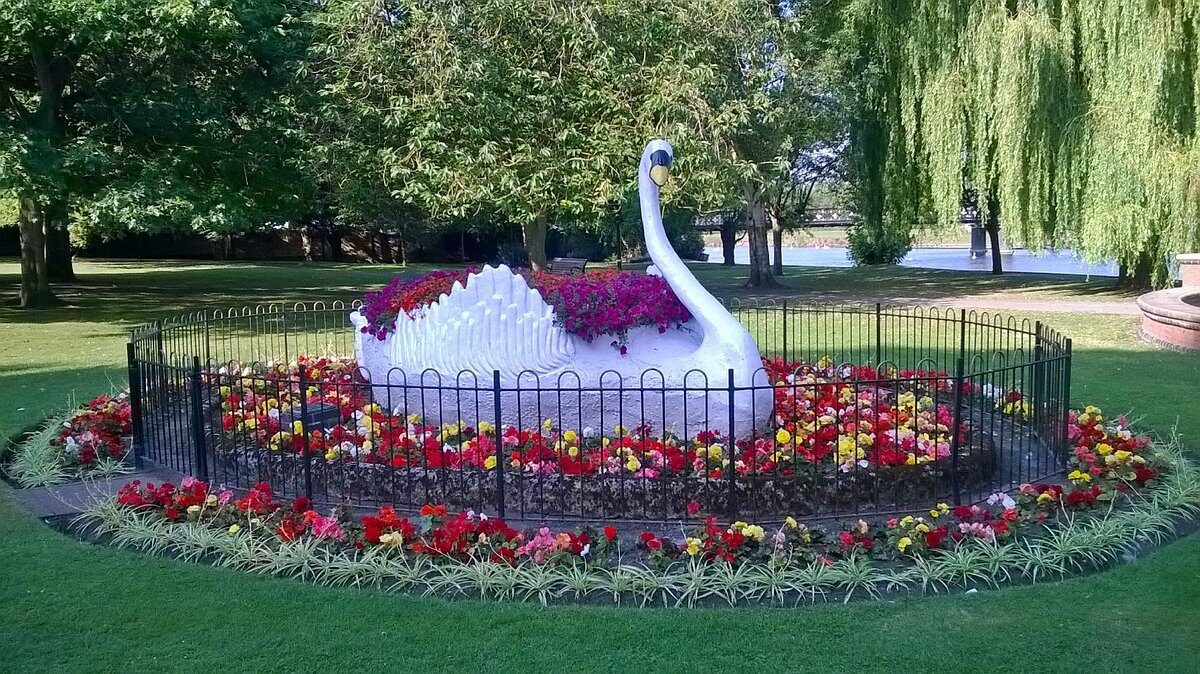 Statue of a swan in a bed of flowers
