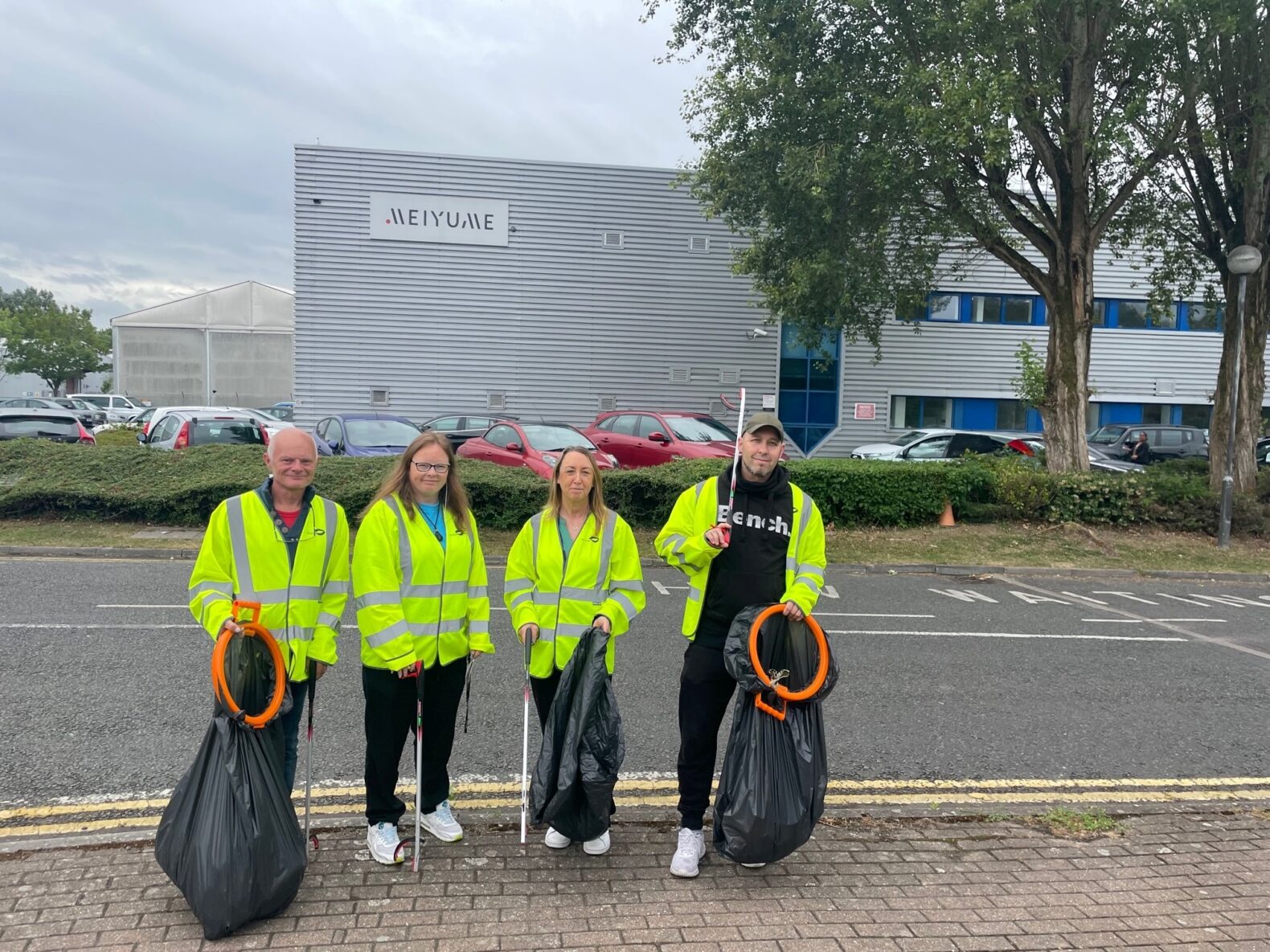 people in hi-vis holding bin bags litter picking