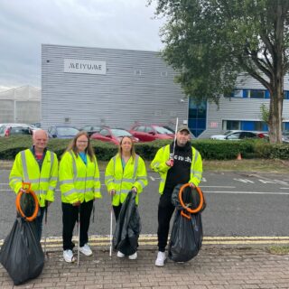 people in hi-vis holding bin bags litter picking
