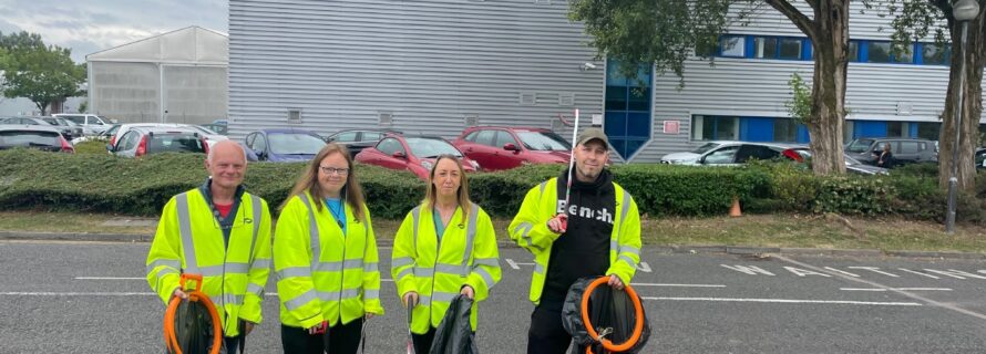 people in hi-vis holding bin bags litter picking