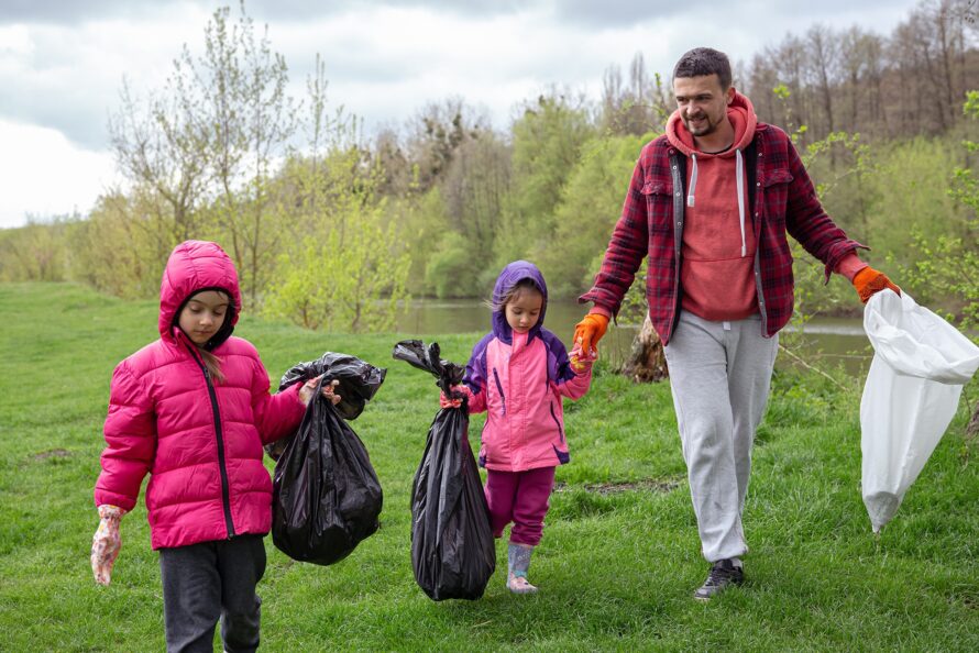 Two,Little,Girls,With,Their,Dad,,With,Garbage,Bags,On